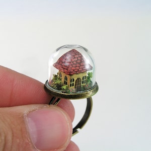 Miniature world. Tiny little house amidst garden in a glass dome ring.