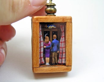 Miniature romantic scene pendant, a tiny man embraces a tiny woman while watching the starry sky out a window in a tiny box frame