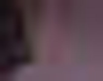May include: A porcelain doll with dark brown curly hair, wearing a pink dress with a white collar and a pink bow headband.