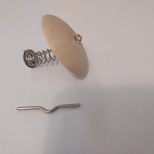 May include: A wooden disc with a metal spring and a small metal loop attached. A separate metal piece with a V-shape is also included.