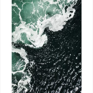 Op de afbeelding: Luchtfoto van oceaangolven. De afbeelding legt het contrast vast tussen het donkere, diepe water en de schuimige witte toppen van de golven. Het water gaat over van een diepblauwgroen naar een donkere, bijna zwarte kleur.