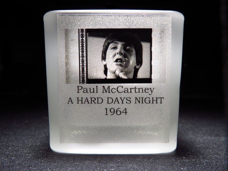May include: A frosted glass paperweight with a black and white photo of Paul McCartney from the movie "A Hard Days Night" released in 1964.