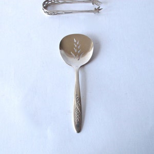 Puede incluir: Cuchara de servir de plata con un diseño de trigo y un cuenco ranurado. La cuchara tiene un mango decorativo con un diseño de trigo.