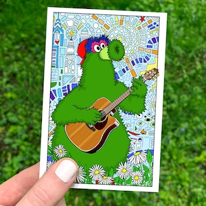 May include: A colorful illustration of a green, furry creature playing an acoustic guitar. The creature wears a red cap and has a large, round nose. The background features a mosaic-style design with various shapes and colors, and a field of daisies.