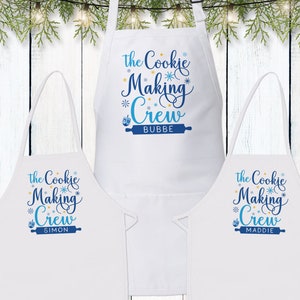 May include: Three white aprons with blue and yellow text that reads "The Cookie Making Crew" with a personalized name below. The names are Simon, Bubbe, and Maddie.