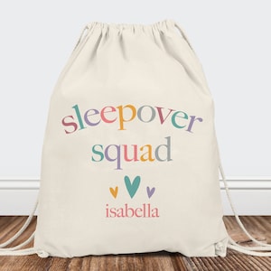 May include: A white drawstring bag with the text "sleepover squad" in rainbow colors and the name "isabella" in pink below. There are four small hearts in different colors above the name.
