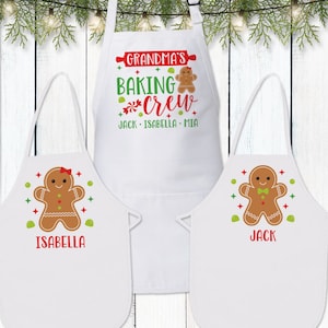 May include: Three white aprons with gingerbread people designs. The top apron says "Grandma's Baking Crew Jack - Isabella - Mia". The bottom two aprons say "Isabella" and "Jack".