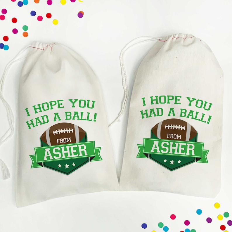 K&ouml;nnte beinhalten: Zwei wei&szlig;e Kordelbeutel mit gr&uuml;nen und braunen Fu&szlig;ballmotiven. Die Beutel haben den Text "Ich hoffe, du hattest Spa&szlig;!" und "Von Asher" aufgedruckt.