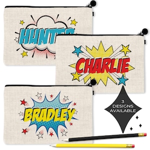 May include: Three rectangular beige canvas pencil pouches with black zippers. Each pouch features a comic book style graphic with a name: Hunter in blue, Charlie in red, and Bradley in yellow. A black diamond graphic reads 3 DESIGNS AVAILABLE.