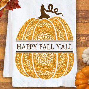 May include: A white kitchen towel featuring a large orange pumpkin graphic with intricate white mandala-style patterns. A brown stem sits atop the pumpkin, and the text HAPPY FALL Y'ALL is printed in brown letters across a horizontal centre bar.