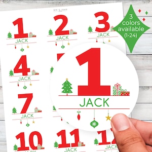 Puede incluir: Hoja de pegatinas blancas con los números rojos 1, 2, 3, 4, 7, 10, 11 y 12. Cada número tiene el nombre "JACK" debajo, junto con un árbol de Navidad, regalos y adornos. El texto "3 colores disponibles (1-24)" está en un rombo verde.