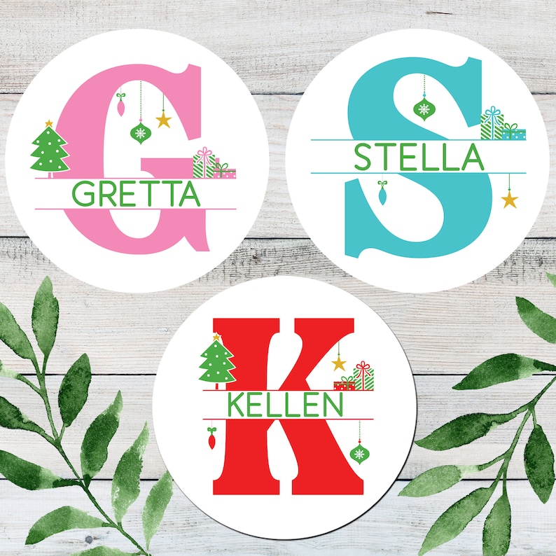May include: Three round Christmas ornaments with a white background and a large letter in the center. The letters are G, S, and K. Each letter is a different color: pink, blue, and red. Each ornament has a Christmas tree, a star, and a gift box on the top and bottom of the letter. The names "Gret