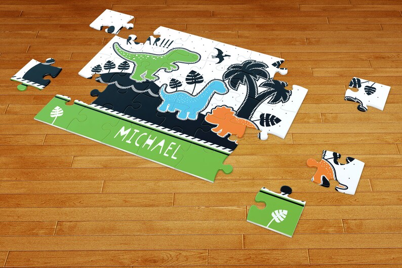 May include: A jigsaw puzzle featuring a green dinosaur, a blue dinosaur, and an orange dinosaur with palm trees and the text ROAR!!! and MICHAEL. The puzzle pieces are white, green, blue, orange, and black with a graphic illustration of prehistoric life.