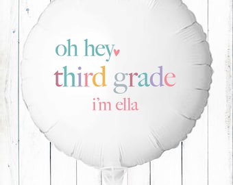 May include: White, round balloon with the text "oh hey third grade i'm ella" in colourful letters. The balloon has a heart symbol next to "hey". The balloon is on a white background.