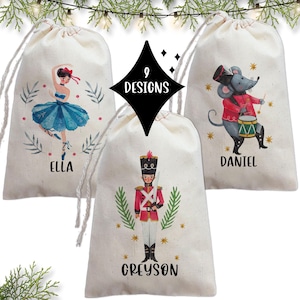 May include: Three personalized Christmas gift bags with different designs. The first bag features a ballerina with the name Ella, the second bag features a toy soldier with the name Greyson, and the third bag features a mouse playing a drum with the name Daniel.