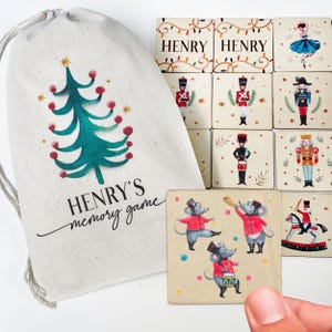 May include: A personalized Christmas-themed memory game with a drawstring bag. The bag is white with a green Christmas tree and the text "HENRY'S memory game". The game tiles feature illustrations of a nutcracker, a ballerina, a mouse, and a Christmas tree.