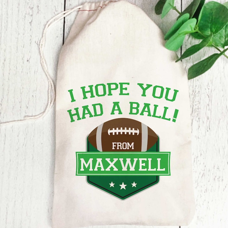 K&ouml;nnte beinhalten: Wei&szlig;e Baumwolltasche mit Kordelzug und gr&uuml;nem und braunem Motiv eines Fu&szlig;balls. Der Text lautet "Ich hoffe, du hattest Spa&szlig;!" und "Von Maxwell" mit drei Sternen.