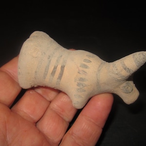May include: A small, hand-painted ceramic figurine of a bull with black and white stripes. The figurine is made of a light brown clay and has a slightly textured surface.