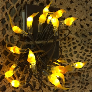 May include: A string of yellow flame-shaped Christmas lights with a brown wire. The lights are wrapped around a brown box.