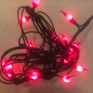 May include: A string of red flame-shaped Christmas lights with black wire. The lights are tangled together.