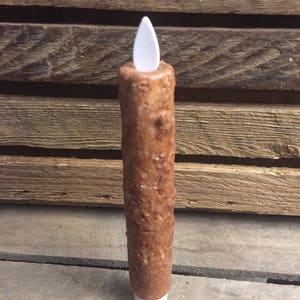 May include: A brown, textured, battery-operated candle with a white LED flame.