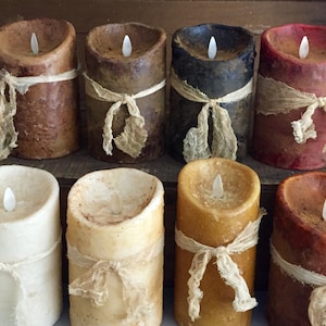 May include: Eight pillar candles with a rustic, distressed finish. Each candle has a burlap ribbon tied around the middle and a flickering LED light inside.
