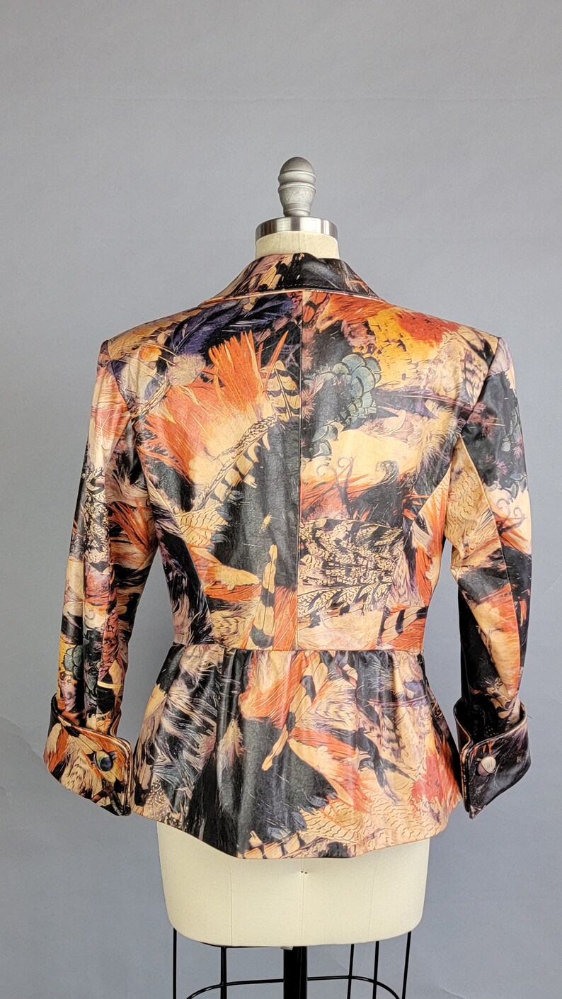 May include: A brown, black, and orange patterned jacket with a fitted waist and long sleeves. The jacket has a button closure and a collar.