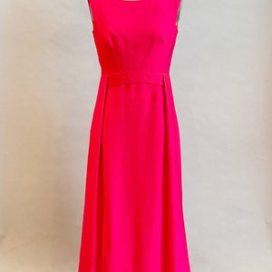 May include: A sleeveless, floor-length, hot pink dress with a simple, fitted bodice and a slightly flared skirt.