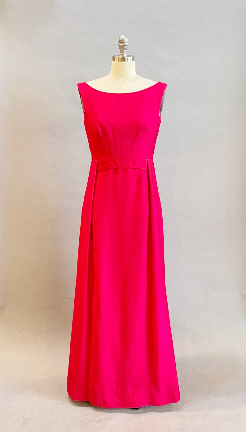 May include: A sleeveless, floor-length, hot pink dress with a simple, fitted bodice and a slightly flared skirt.