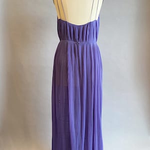May include: A long, purple, pleated dress with thin straps. The dress is made of a lightweight fabric and has a flowing silhouette.