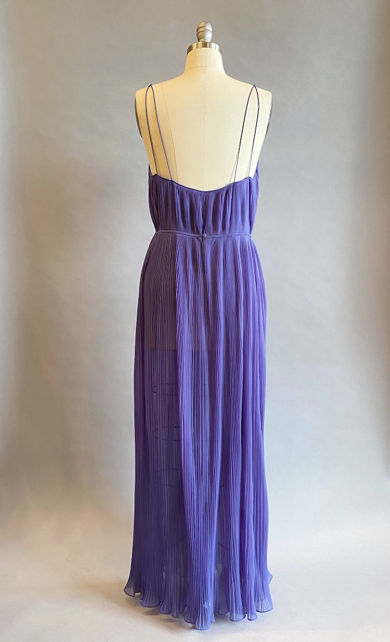 May include: A long, purple, pleated dress with thin straps. The dress is made of a lightweight fabric and has a flowing silhouette.