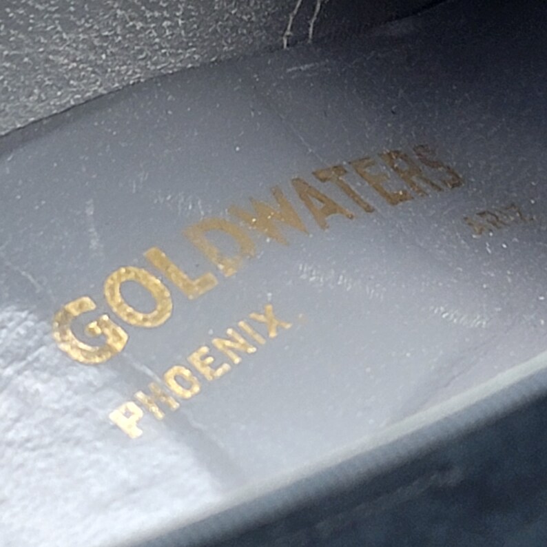 K&ouml;nnte beinhalten: Nahaufnahme einer grauen Ledereinlegesohle mit dem Schriftzug "Goldwaters Phoenix" in goldener Schrift.