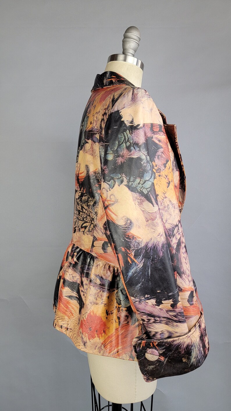 May include: A brown, black, and orange patterned jacket with a ruffled hem and long sleeves. The jacket is on a white mannequin.