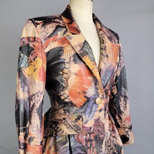 May include: A fitted blazer with a colorful feather print. The blazer has a single button closure and long sleeves with a cuffed hem.