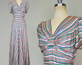 May include: A long, striped dress with a V-neckline and short sleeves. The dress has a fitted bodice and a flowing skirt. The stripes are in shades of pink, green, blue, and white.