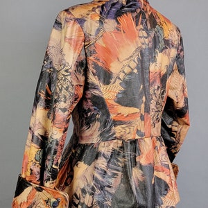May include: A brown leather jacket with a colorful feather print. The jacket has a fitted waist and long sleeves with cuffed ends.