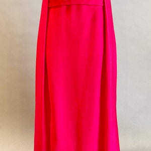 May include: A long, sleeveless, bright pink dress with a simple design and a narrow belt at the waist.