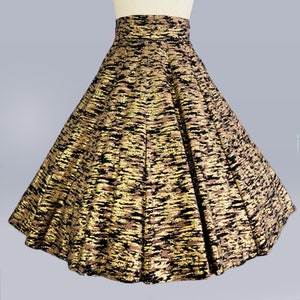 May include: A full-length skirt with a high waist and a black and gold metallic print. The skirt is made of a flowing fabric and has a wide, circular shape.