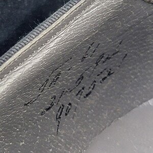 K&ouml;nnte beinhalten: Nahaufnahme einer grauen, strukturierten Oberfl&auml;che mit handschriftlichem Text, der "Made in Italy 901 1932" lautet.