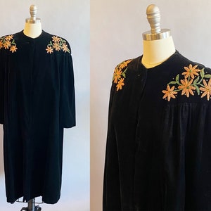 May include: A black velvet jacket with embroidered orange and green flowers on the shoulders. The jacket has a long, fitted silhouette and a button-up front.