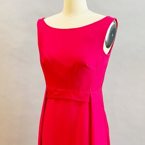 May include: A sleeveless, bright pink dress with a simple, fitted bodice and a slightly flared skirt. The dress has a narrow belt at the waist.