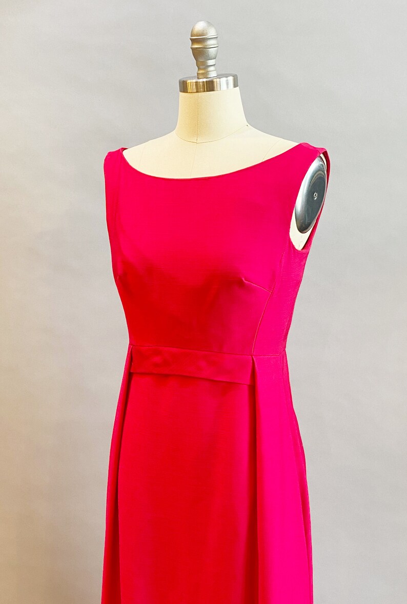 May include: A sleeveless, bright pink dress with a simple, fitted bodice and a slightly flared skirt. The dress has a narrow belt at the waist.