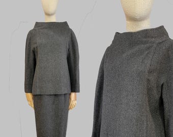 May include: A gray wool suit with a high neck and long sleeves. The suit is tailored and has a classic look.