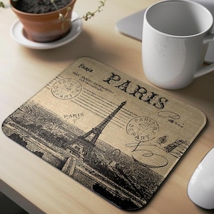 May include: A brown and beige mouse pad with a vintage Parisian theme. The mouse pad features a black and white illustration of the Eiffel Tower and the word "Paris" in a stylized font.