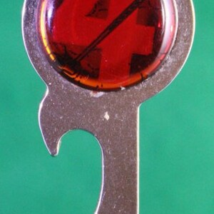 May include: A silver bottle opener keychain with a red, round, glass charm featuring a number four.