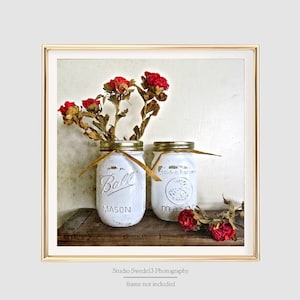 May include: Two white painted mason jars with red dried flowers, one jar says "Ball Mason" and the other says "Golden Harvest Mason"