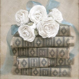 Puede incluir: Una pila de libros antiguos con letras doradas y dise&ntilde;os ornamentados en las cubiertas. Un ramo de rosas de papel blanco con una cinta azul se coloca encima de los libros.