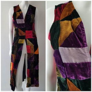 May include: A long, sleeveless vest made of patchwork velvet in shades of purple, green, red, brown, and gold. The vest has a deep V-neck and a front slit.