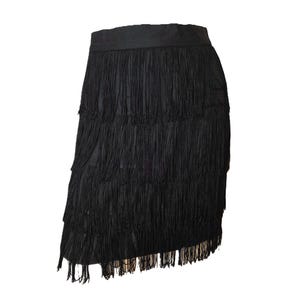May include: Black mini skirt with multiple layers of long fringe. The skirt has a solid waistband and a short, straight silhouette. This garment is suitable for dance or party wear.