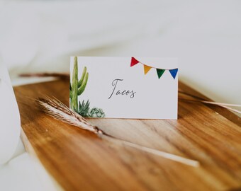 May include: A white card with a green cactus and succulents illustration, a string of colorful pennants, and the word "Tacos" written in black cursive.